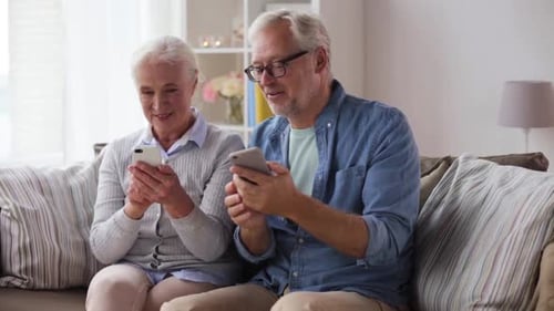 Senior Couple Using Smartphones Together on Sofa at Home