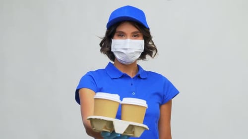 Woman in mask offering takeaway coffees