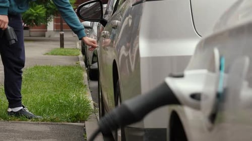 Electric Car Being Disconnected From Charger on City Street