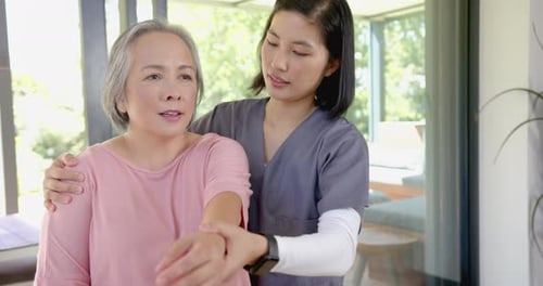 Health Professional Stretching Senior Woman's Arm Indoors