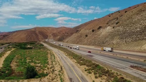 A highway with trucks and cars between hills. Heavy transport in California.