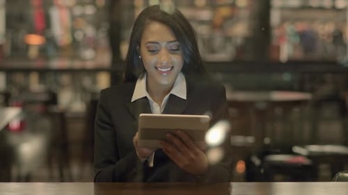 Woman Smiling and Using a Tablet Indoors