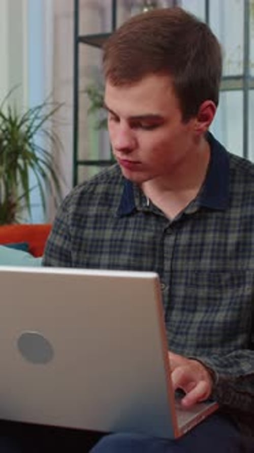 Young Man Freelancer Sitting on Sofa Closing Laptop Pc After Finishing Work in Living Room at Home