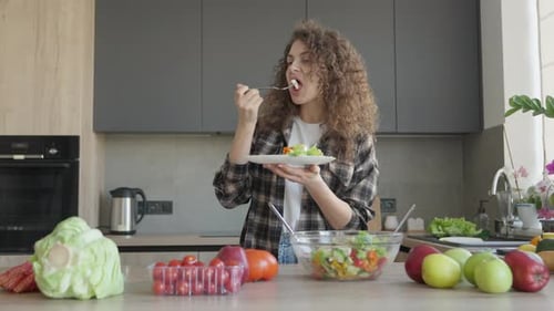 Woman in Kitchen Eating Fresh Salad