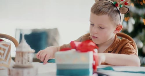 Boy Opens Christmas Gift with Festive Joy