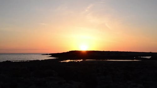 Sunrise on the stones in front of the sea capturing sun rising behind small island