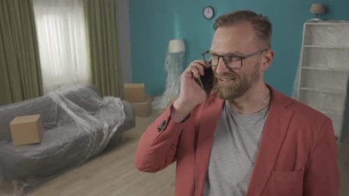 A Selfconfident Realtor Standing in a New Apartment Speaks on the Phone with Potential Clients