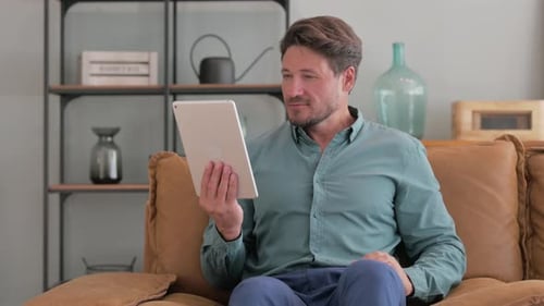 Man Using Tablet While Relaxing on Couch at Home