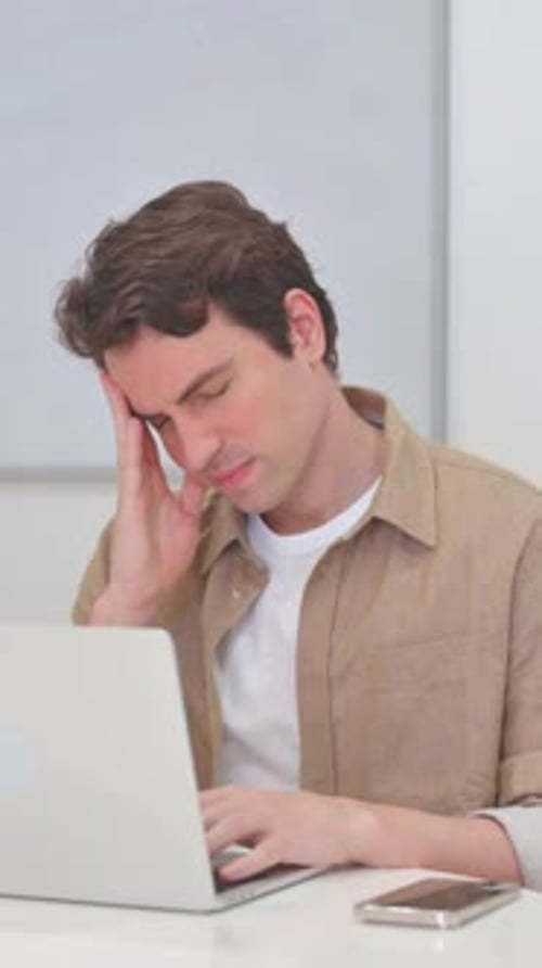Man with Headache Working on Laptop at Desk