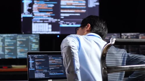 Programmer Having A Backache While Writing Code By A Laptop Using Multiple Monitors Showing Database