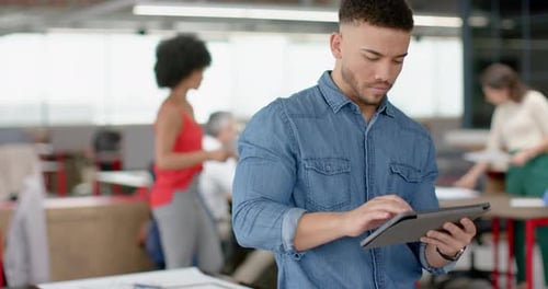 Portrait of biracial man using a digital tablet and smiling at office