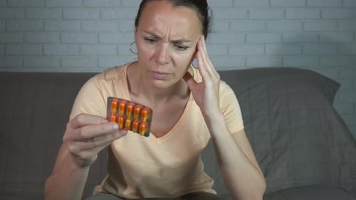 Mature Woman Looks at Pills in Blister Pack