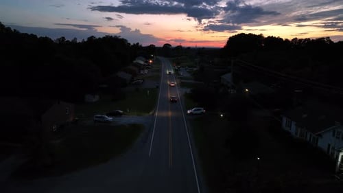 Traffic on sunset time in American suburb. Aerial wide shot. Driving cars on intersection road.