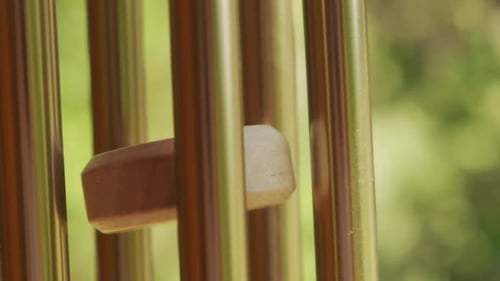 Metal wind chime closeup natural green background slow motion 120p