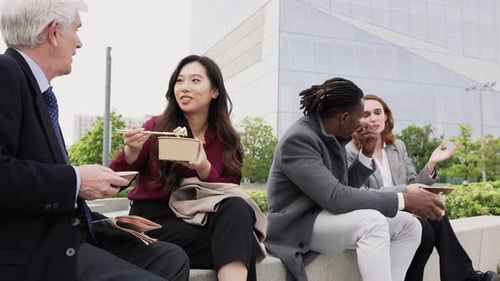 Happy multiracial business people having a lunch break outside office