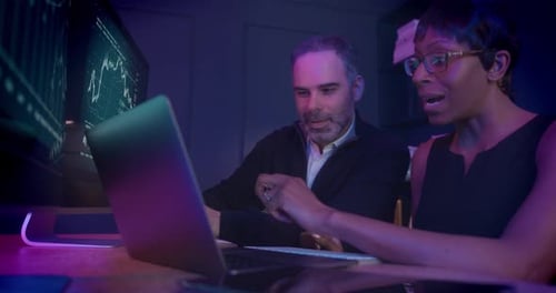 Business People Working Late at Night in Office looking at Performance Charts