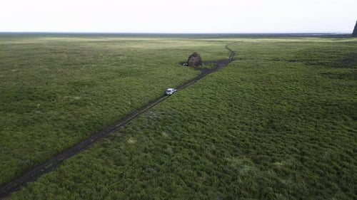 Aerial View of a Solitary Car Crossing a Vast Icelandic Landscape