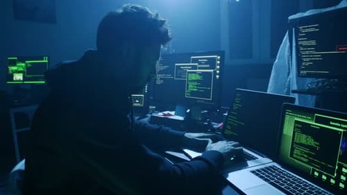 A Cybersecurity Expert Working Late at Night Surrounded By Multiple Computer Screens and Devices