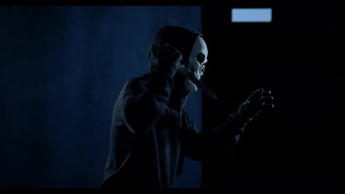 Side View Of Scary Man Wearing Ghost Mask Holding A Knife While Walking In The Abandoned Hotel