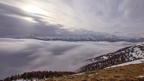 Long exposure time lapse of low-lying fog in a valley below the mountains