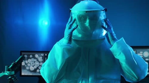 Lab Worker Removes Protective Gear in Blue Light