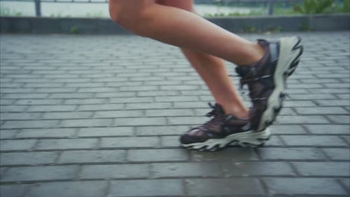 Dynamic Closeup of a Runner's Legs in Motion Showcasing Athletic Shoes on a Pavement Path