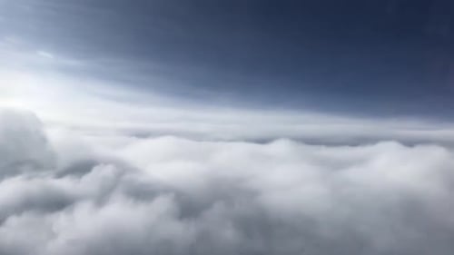 Eine atemberaubende Luftaufnahme über den Wolken, die weiche, flauschige Gebilde zeigt, die sich bis in die Sonne erstrecken