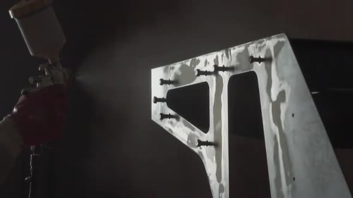 Employee Paints Metal Detail with Air Brush in Workshop