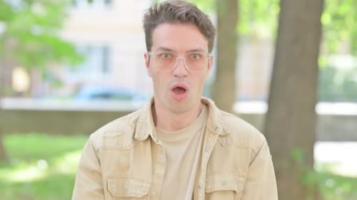Young Man Reacts with Shock and Surprise Outdoors