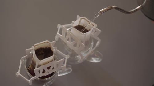 Top View of Pouring Hot Water From Gooseneck Kettle Into Disposable Drip Coffee Filter Bag Preparing