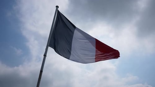 Nahaufnahme der französischen Flagge, die im Wind weht, vor dem Hintergrund des blauen, bewölkten Himmels im sonnigen Sommer