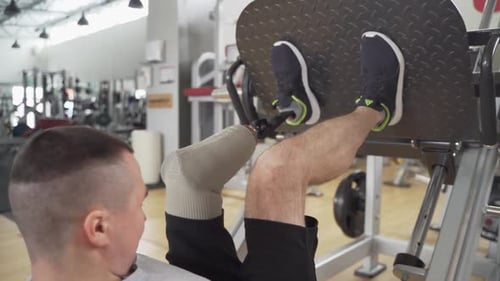 Disabled athletic with prosthetic leg do heavy exercises for legs at the gym in slow motion