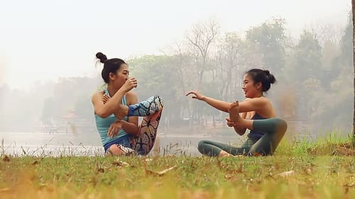 Two Women Stretching by Lake Outdoors