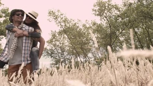 Happy caucasian couple piggybacking and laughing together in sunny field