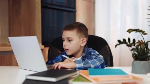 Young Boy Studies at Desk with Laptop