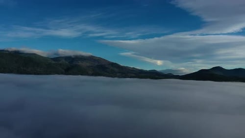 Drohnenflug über den Wolken, der die höchsten Berge visualisiert und ein Wolkenmeer als Boden hinterlässt