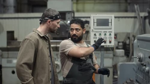 Travailleur masculin montrant comment utiliser une fraiseuse CNC à un employé
