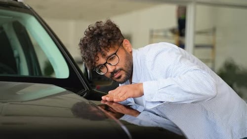 Arabian Customer Inspecting Car Paint in Dealership Showroom