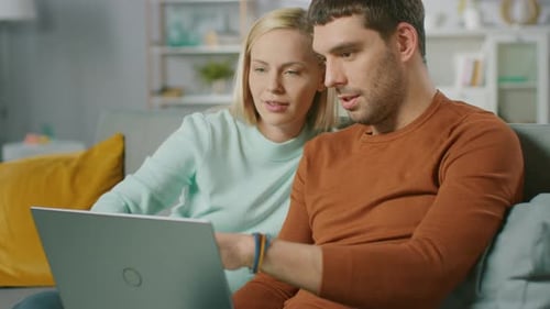 Couple Browsing Laptop Together on Couch Indoors