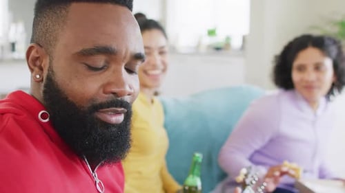 Happy diverse female and male friends playing guitar and laughing at home in slow motion