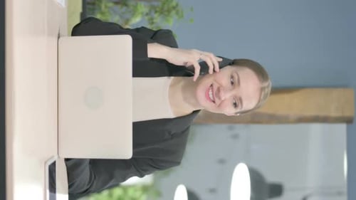 Woman Smiling, Talking on Phone at Desk