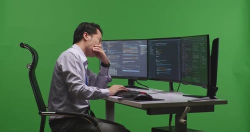 Developer Yawning Before Sleeping While Write Code With Multiple Computer Screens In Green Screen
