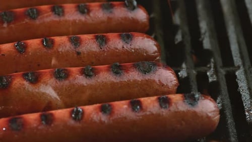 Super slow motion phantom flex 4k shot of hot dogs cooking on a grill