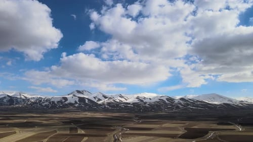 Aerial View of Rural Fields with Snow-Capped Mountains