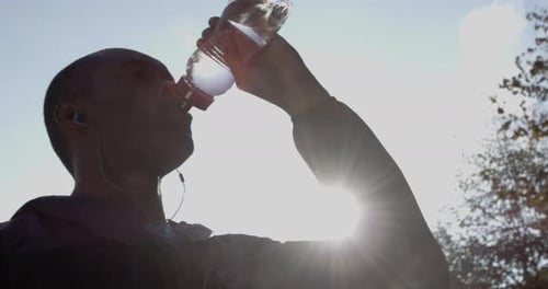 Man Drinks Water After Workout on Sunny Day