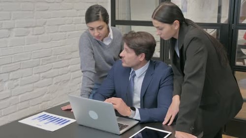 Colleagues Analyzing Data on a Laptop in Office