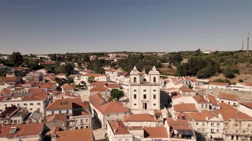 Panoramic aerial pan shot of Santiago church and parish townscape in Alcacer Do Sal, Portugal.