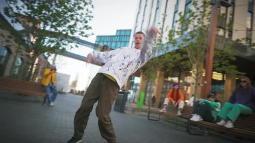 Young And Stylish Male Hip Hop Dancer Is Freestyling On City Street Among Modern Buildings In the