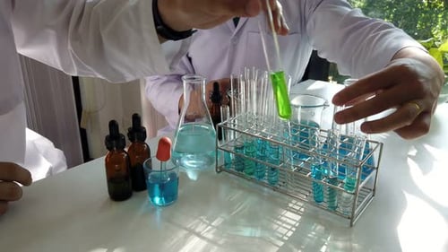 Researcher dropping the reagent or chemical liquid into test tube. Laboratory science, research