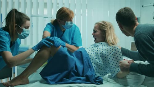 En el hospital, una mujer en trabajo de parto empuja para dar a luz, los obstetras la ayudan, el esposo la sostiene